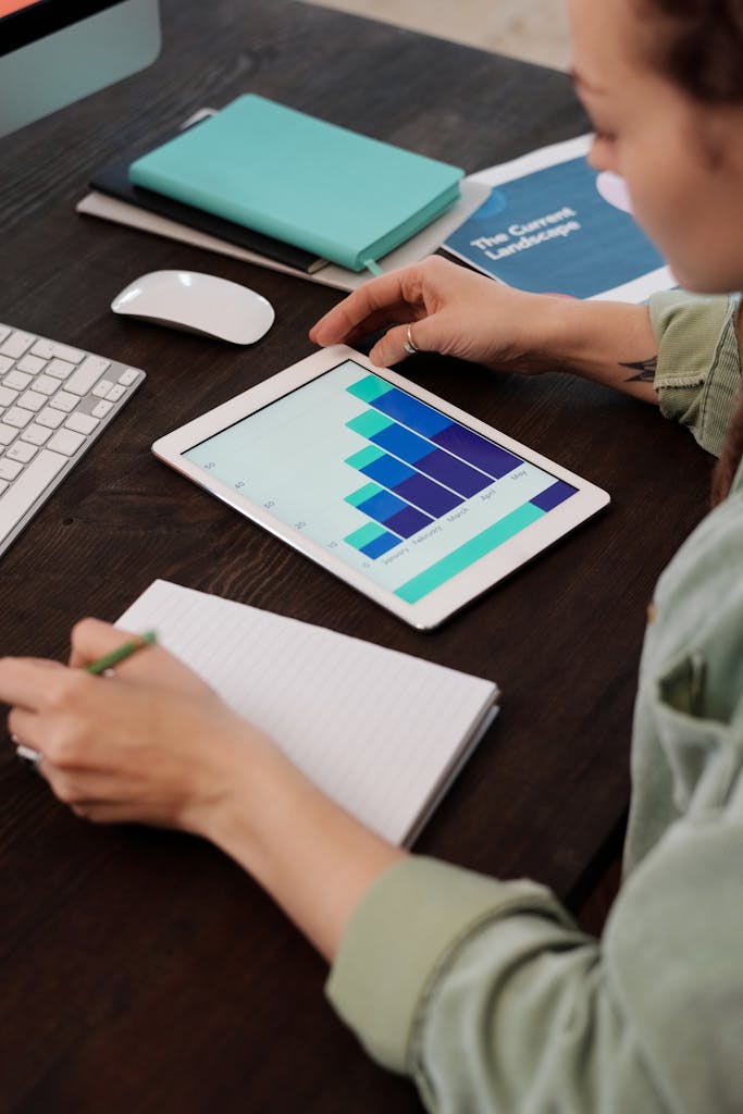 Focused person working on digital tablet analyzing business graphs at desk.