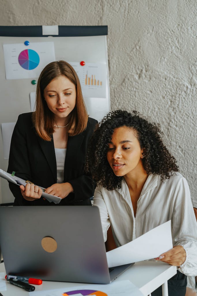 Two confident women working together on a project in a modern office.